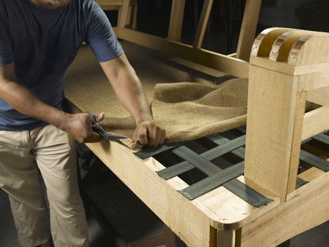 Tapicero trabajando en la estructura de un sofá en el taller